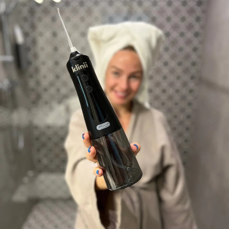 Woman holding the black Klinii Water Flosser